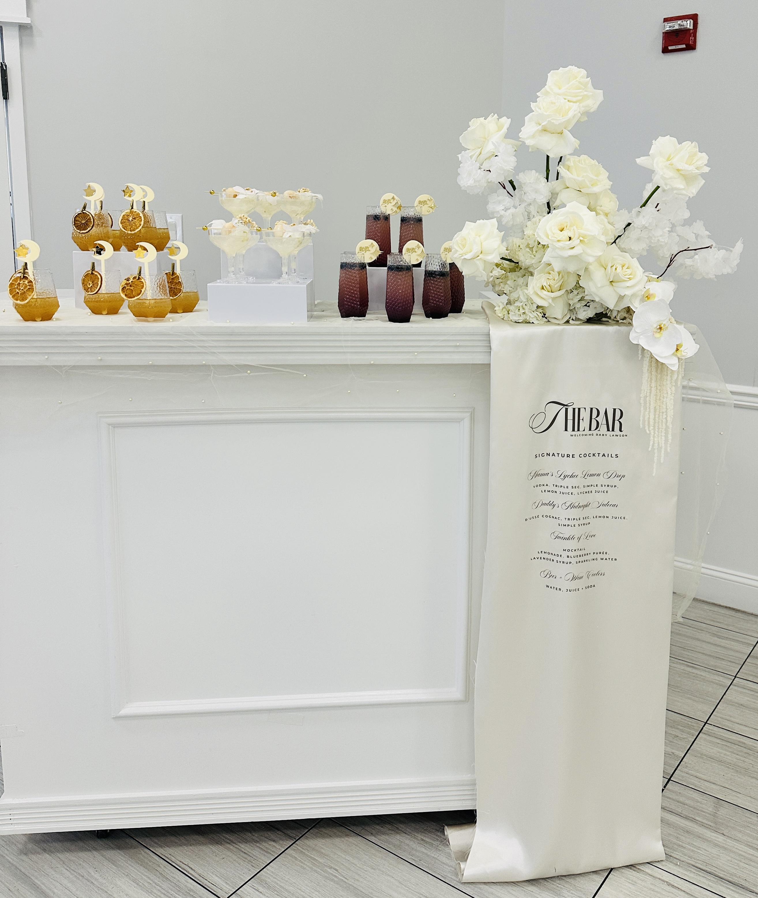 White bar setup with menu sign and floral arrangement